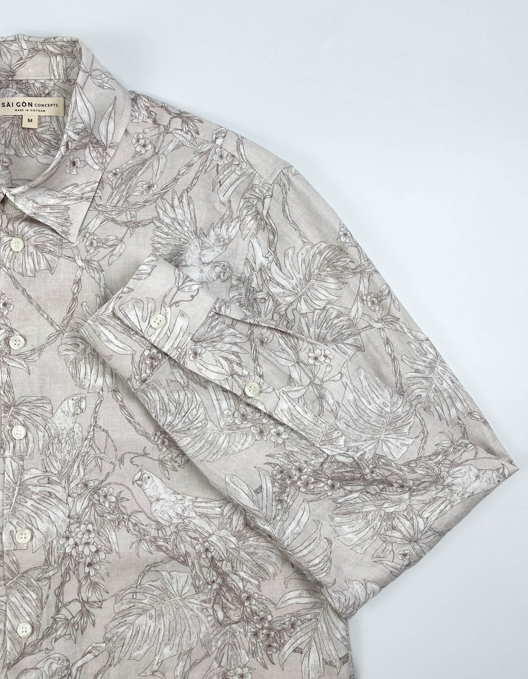 Tropicana Parrot long sleeve button-up shirt lay flat sleeve detail view, parrot and foliage print on natural white linen