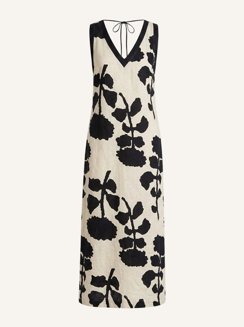 A sleeveless V-neck maxi dress with a black and cream floral print, featuring a tie-neck detail at the back, shown against a plain off-white background.