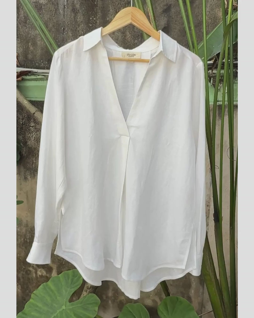 Video showing Saigon Concepts White Linen-mix v-neck long sleeve blouse on hanger in garden showing front view detail 