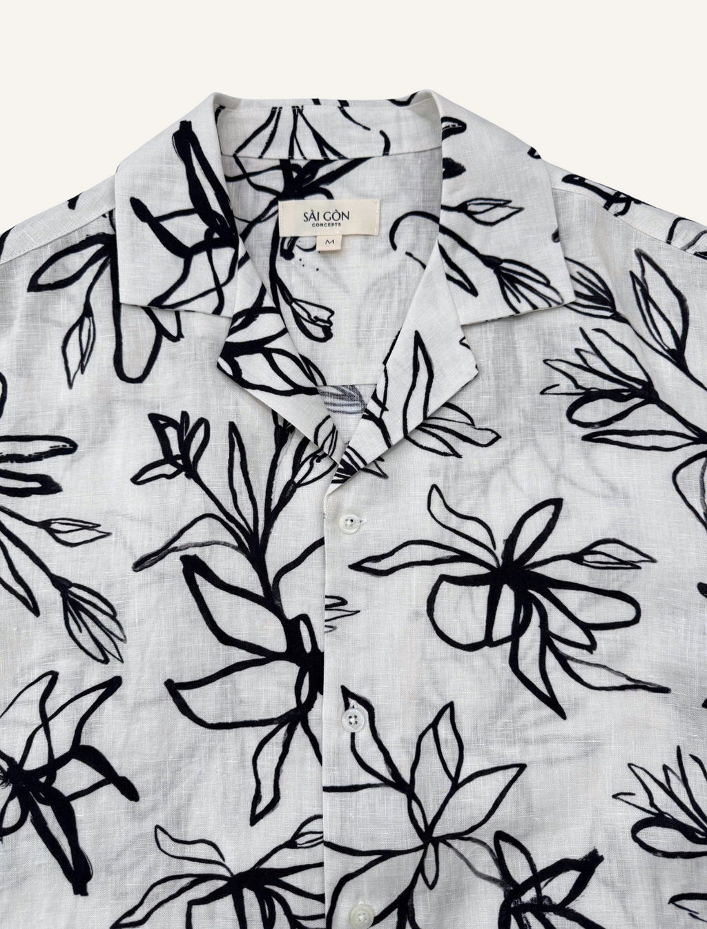 Close-up of camp collar on cream linen Hawaiian shirt with charcoal lily print