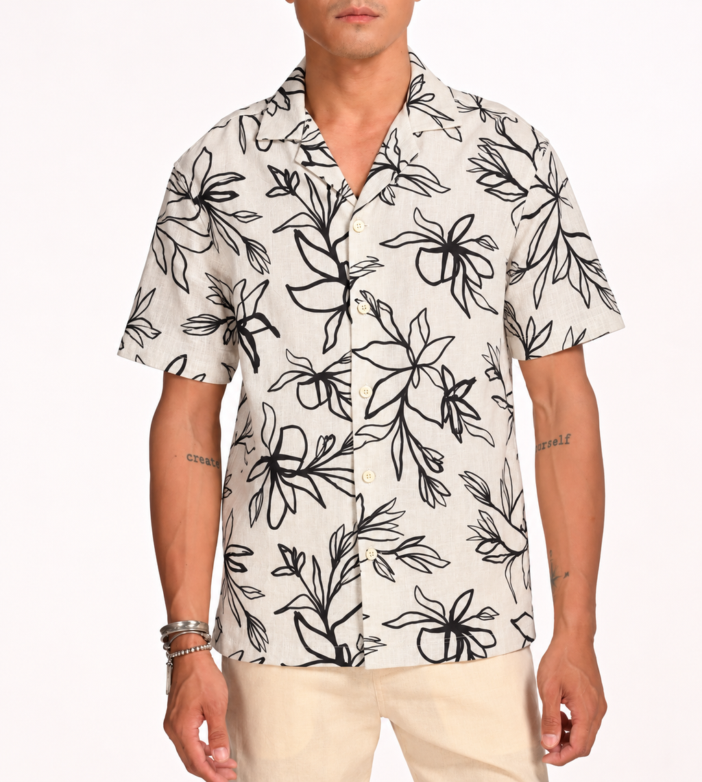 Man wearing cream linen Hawaiian shirt with charcoal lily print, white studio background