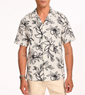 Man wearing cream linen Hawaiian shirt with charcoal lily print, white studio background
