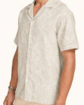 Man wearing ivory linen Hawaiian shirt with tonal white palm leaf print, white studio background