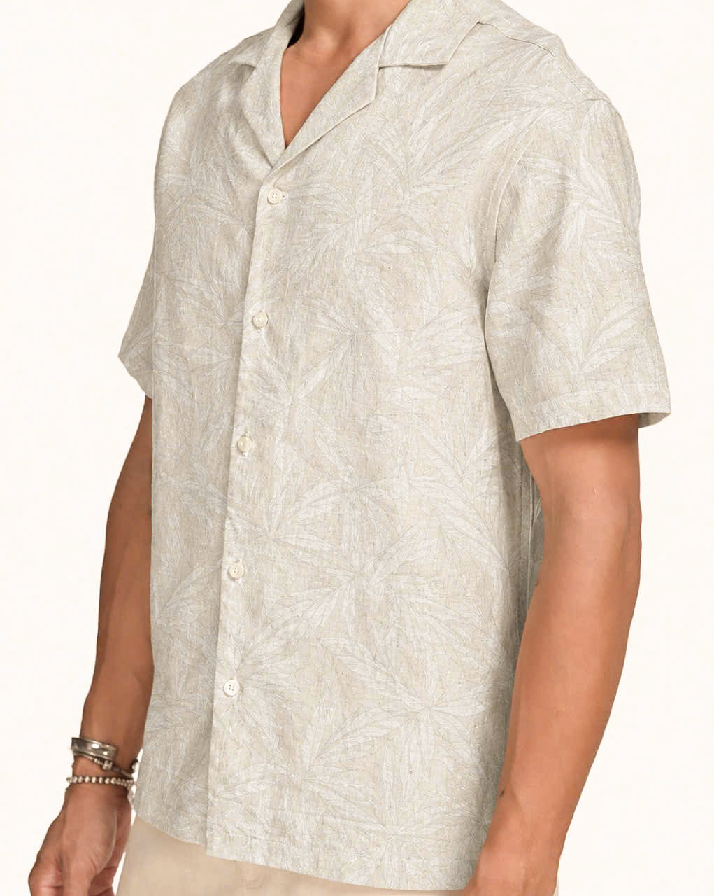Man wearing ivory linen Hawaiian shirt with tonal white palm leaf print, white studio background