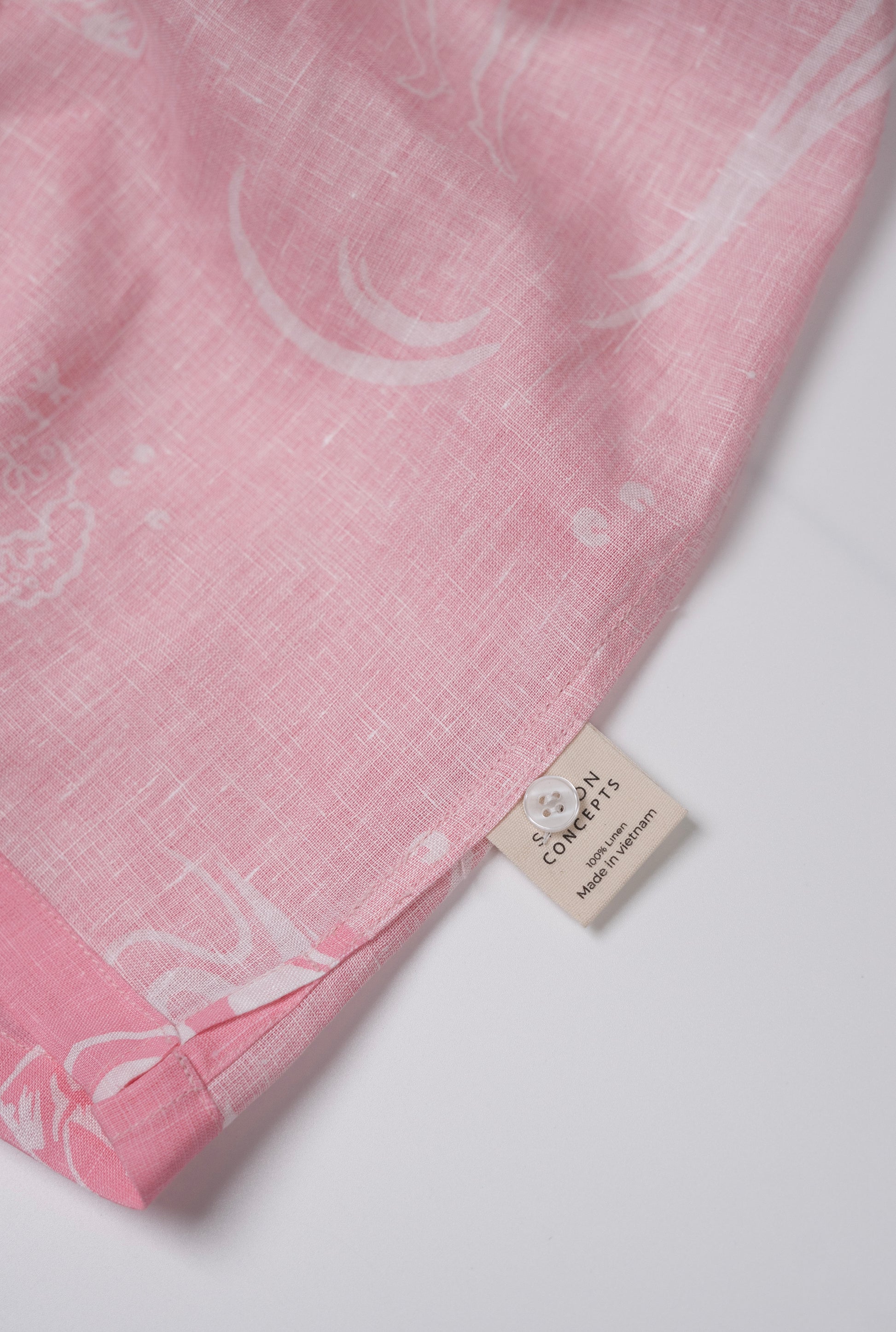 Saigon Concepts Coral Dream 100% Linen Hawaiian Shirt a pink base fabric with while drawn etchings of mermaids, fish and surfers - inside care label detail