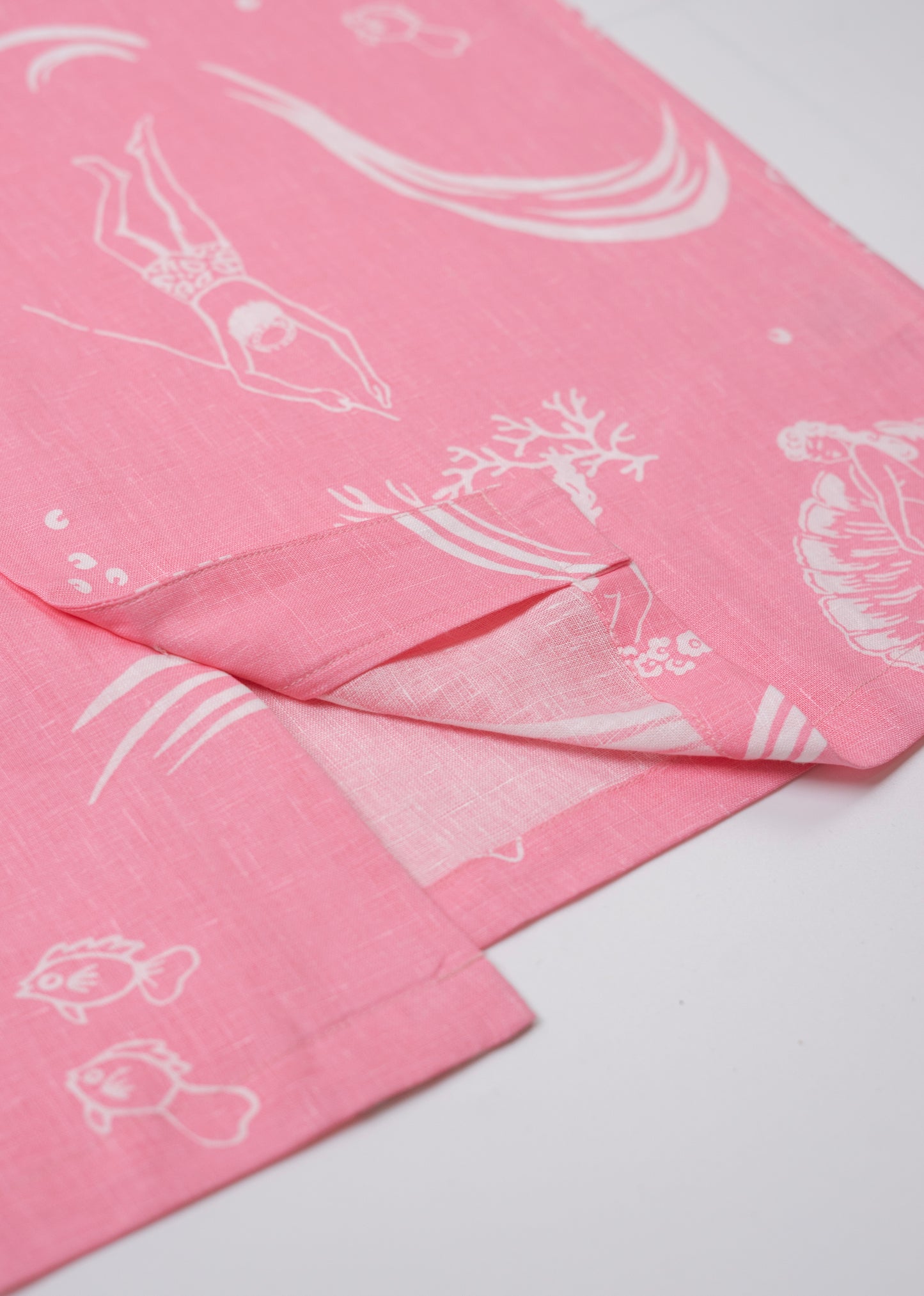 Saigon Concepts Coral Dream 100% Linen Hawaiian Shirt a pink base fabric with while drawn etchings of mermaids, fish and surfers - seam detail view