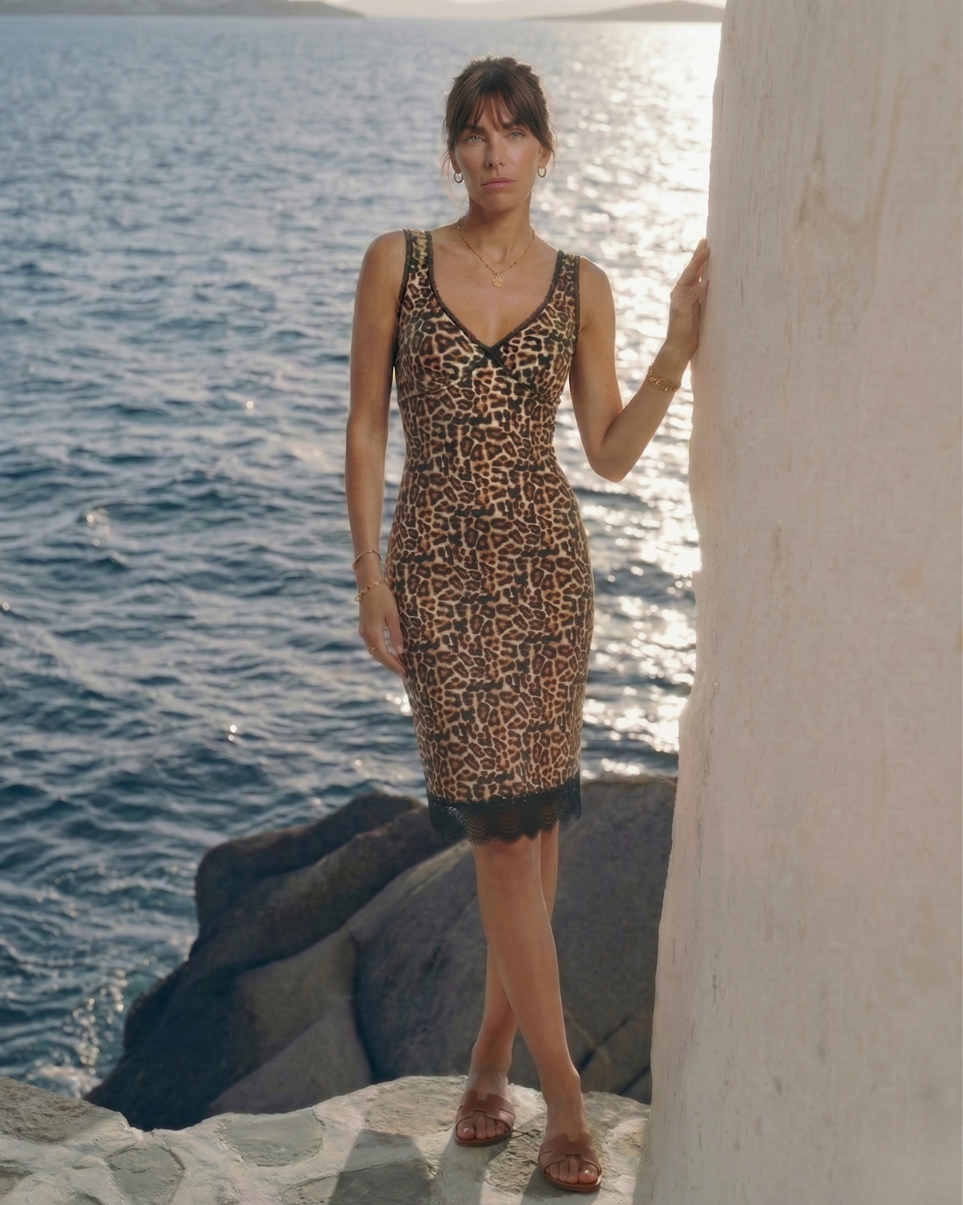 Woman in a leopard print knee-length dress with lace trim standing by the water