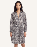 A woman modeling a long-sleeve collared dress with a black and off-white chevron pattern and a matching tie belt, set against a solid off-white background.
